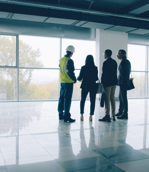 Diverse group of businesspeople standing inside newly constructed industrial building talking discussing real estate. People and business concept.